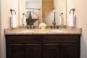 A bathroom with a double sink vanity, dark wood cabinets, and a large mirror above the sink.