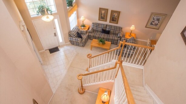 A spacious living area with a checkered sofa set, a coffee table, and a staircase with a wooden railing. - Ip60299 - Highlands Reserve - 5 Bed 2.5 Baths Villa (Davenport)
