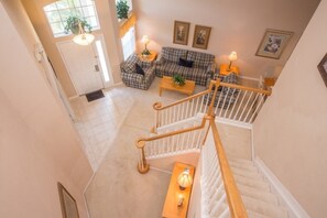 A spacious living area with a checkered sofa set, a coffee table, and a staircase with a wooden railing. - Ip60299 - Highlands Reserve - 5 Bed 2.5 Baths Villa (Davenport)