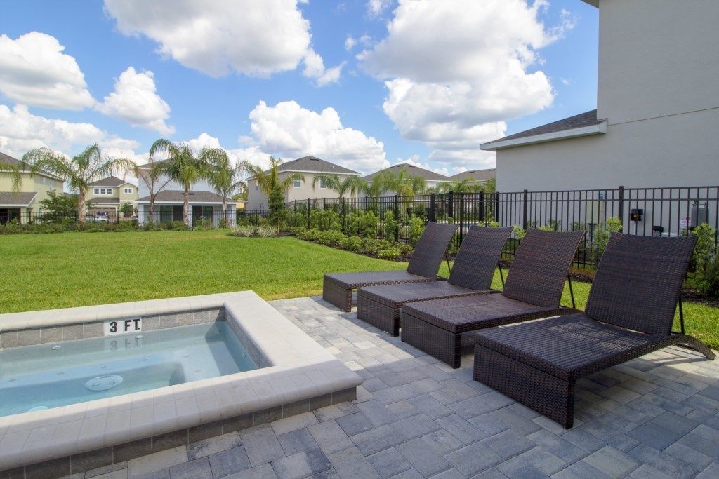 A pool area with lounge chairs and a hot tub.