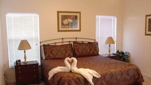 A bedroom with a bed, two bedside tables, lamps, a framed picture, and a potted plant. - Ahr123 - Hampton Lakes - 5 Bed 3 Baths Villa (Davenport)