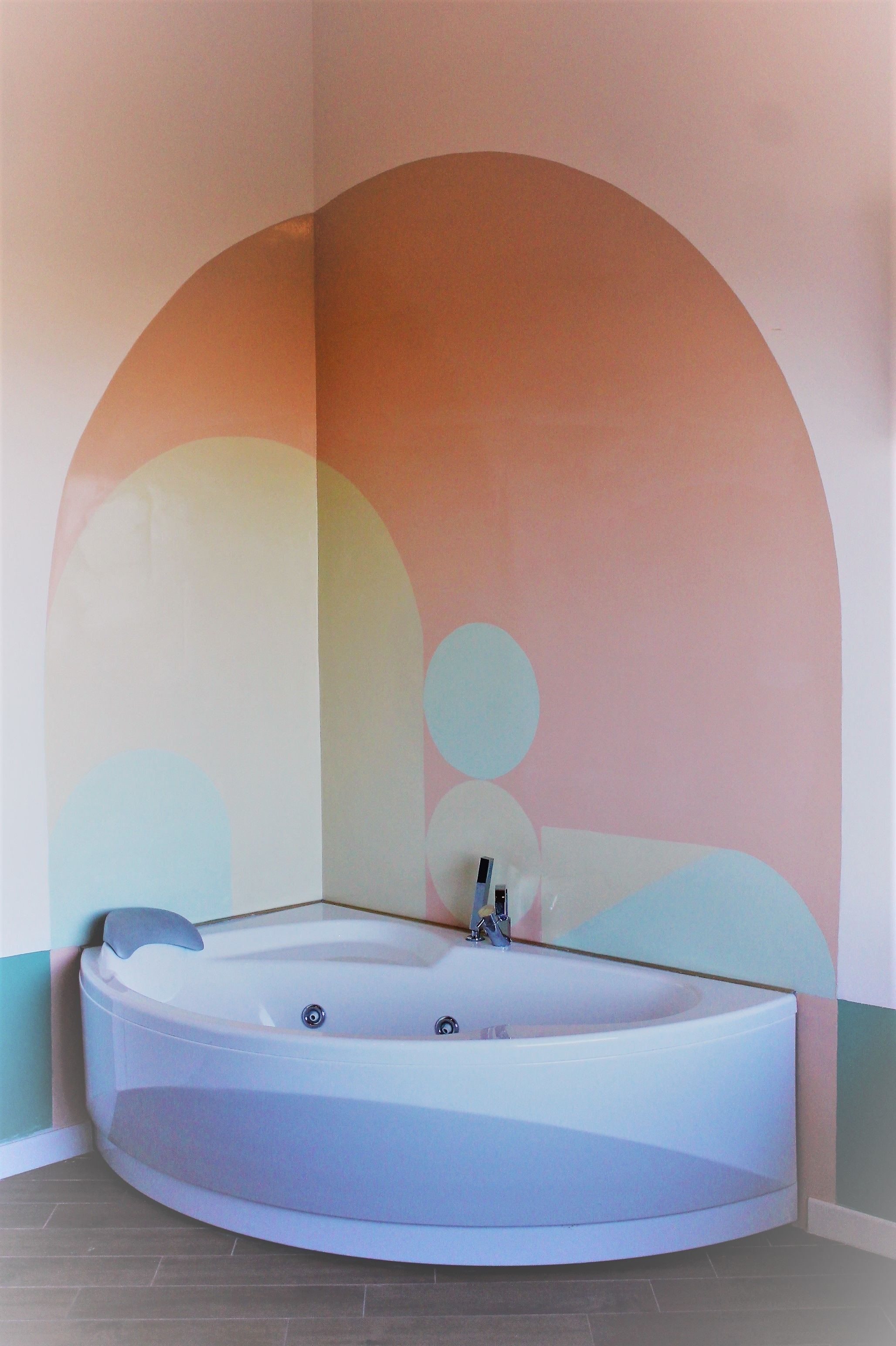 A modern bathroom with a freestanding bathtub, a curved shower area, and a wall with abstract circular designs.