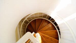 A spiral staircase with wooden steps and a white handrail, leading upwards. - Bora B&B (Troia)