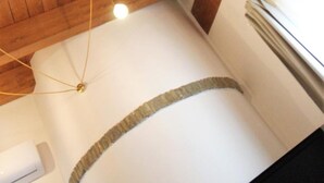 A room with wooden beams on the ceiling, a white wall, and a window with blinds. - Bora B&B (Troia)