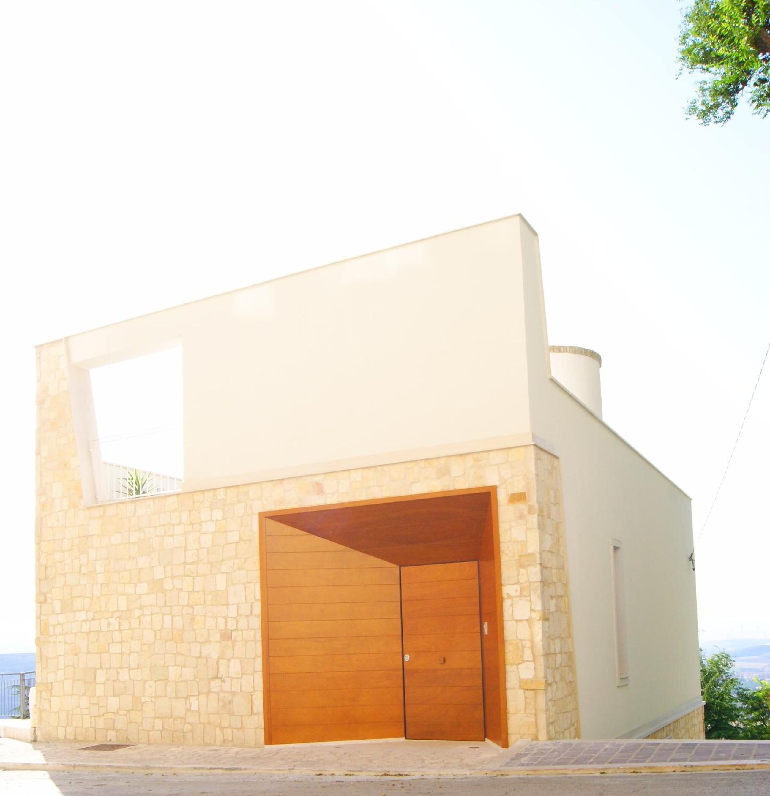 Un bâtiment moderne doté d’une façade en pierre et d’une grande porte de garage en bois.
