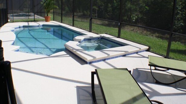 Una piscina amb una banyera d'hidromassatge i gandules.
