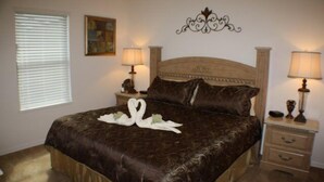 Un llit ben fet amb un edredó marró i dues tovalloles blanques amb forma de cigne. Hi ha dues taules de nit amb làmpades i un objecte decoratiu petit a una d'elles. Un quadre penja a la paret sobre el llit.