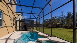 A swimming pool with a glass enclosure, surrounded by a grassy area and a building.