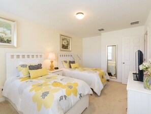 A bedroom with two beds, a nightstand, a lamp, a mirror, and a dresser.