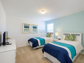 A hotel room with two beds, a TV, a desk, and a window.
