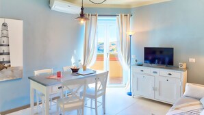 A bright living room with a TV, a dining table, and a sofa. - Golfo Aranci - apartment for 2 people, directly on the beach, with terrace and sea-view (Golfo Aranci)