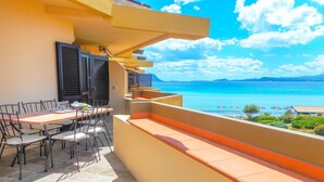 A balcony with a table and chairs, overlooking a clear blue sea and distant mountains. - Golfo Aranci - apartment for 2 people, directly on the beach, with terrace and sea-view (Golfo Aranci)