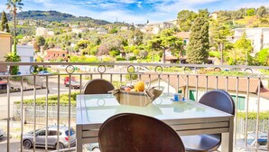 Un balcón con mesa y sillas que da a una zona residencial con casas y vegetación.