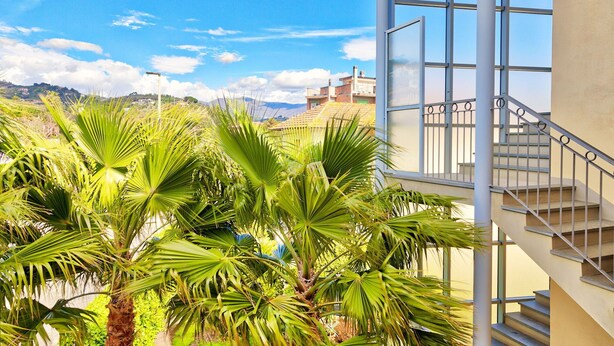 Un edificio moderno con fachada de vidrio, una escalera y vistas a un paisaje montañoso.