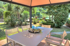 Eine Terrassenanlage im Freien mit einem Tisch für zwei Personen, umgeben von Stühlen, unter einem Sonnensegel.