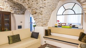 A cozy living room with a stone ceiling, a sofa, a coffee table, and a window with a view.