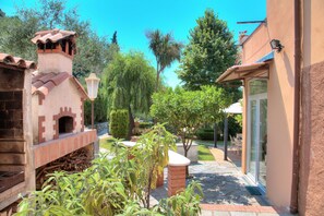 A courtyard with a brick oven, a pergola, and a glass door entrance.