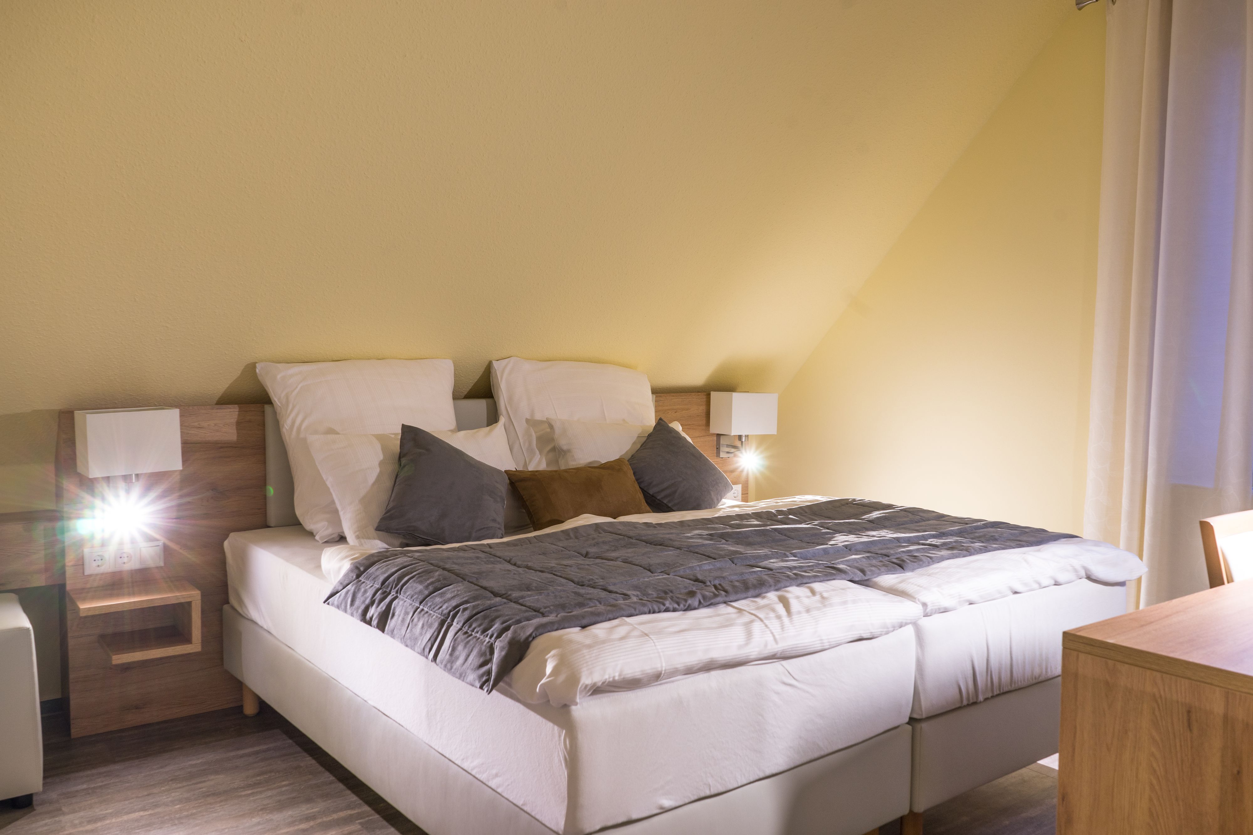 A neatly arranged bedroom with a bed, bedside tables, and a lamp.