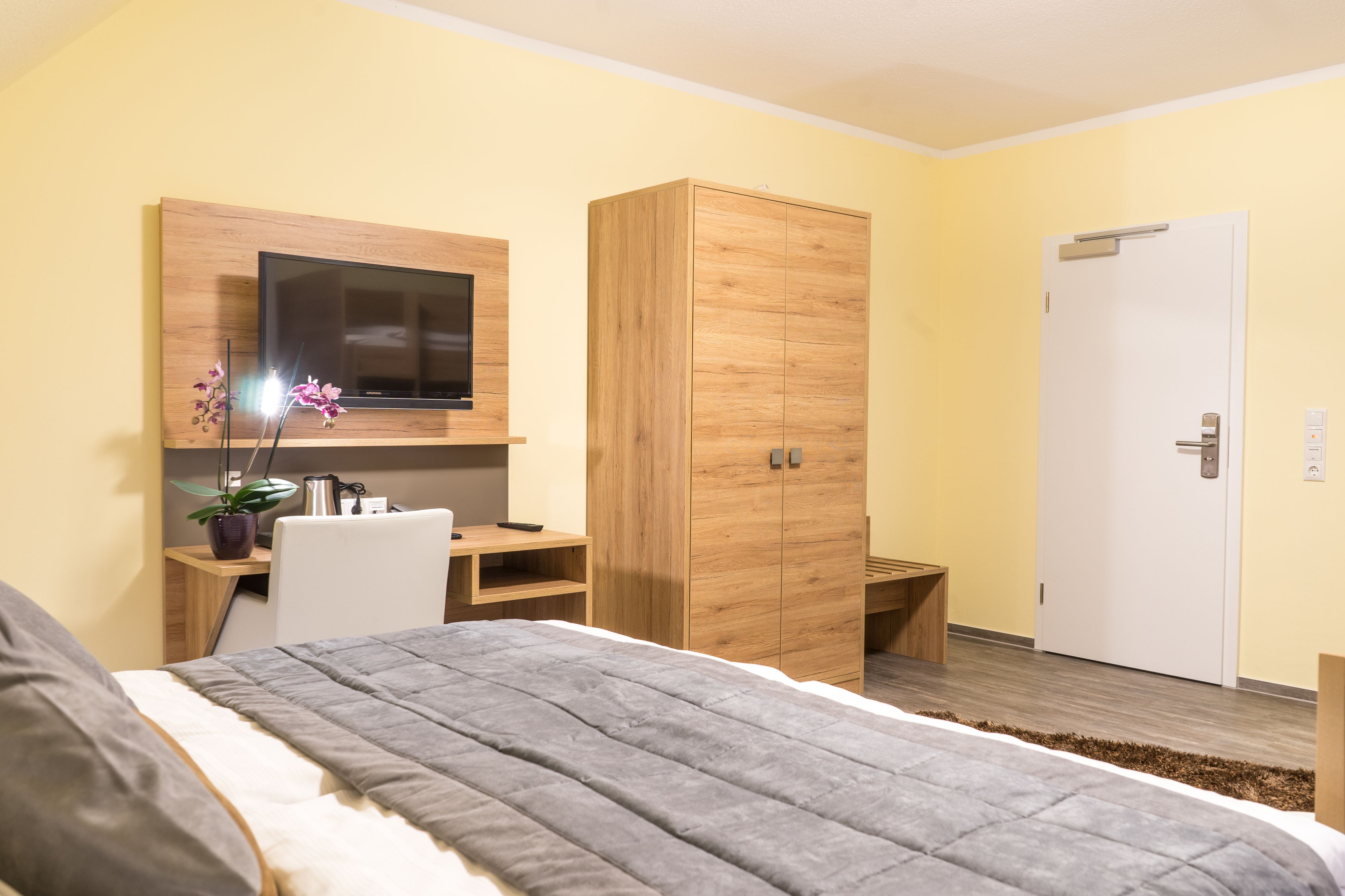 Ein modernes Hotelzimmer mit Bett, Schreibtisch, Fernseher und Kleiderschrank.