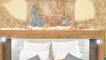 A bed with white and gray pillows, a wooden headboard, and a wall with a stone carving.