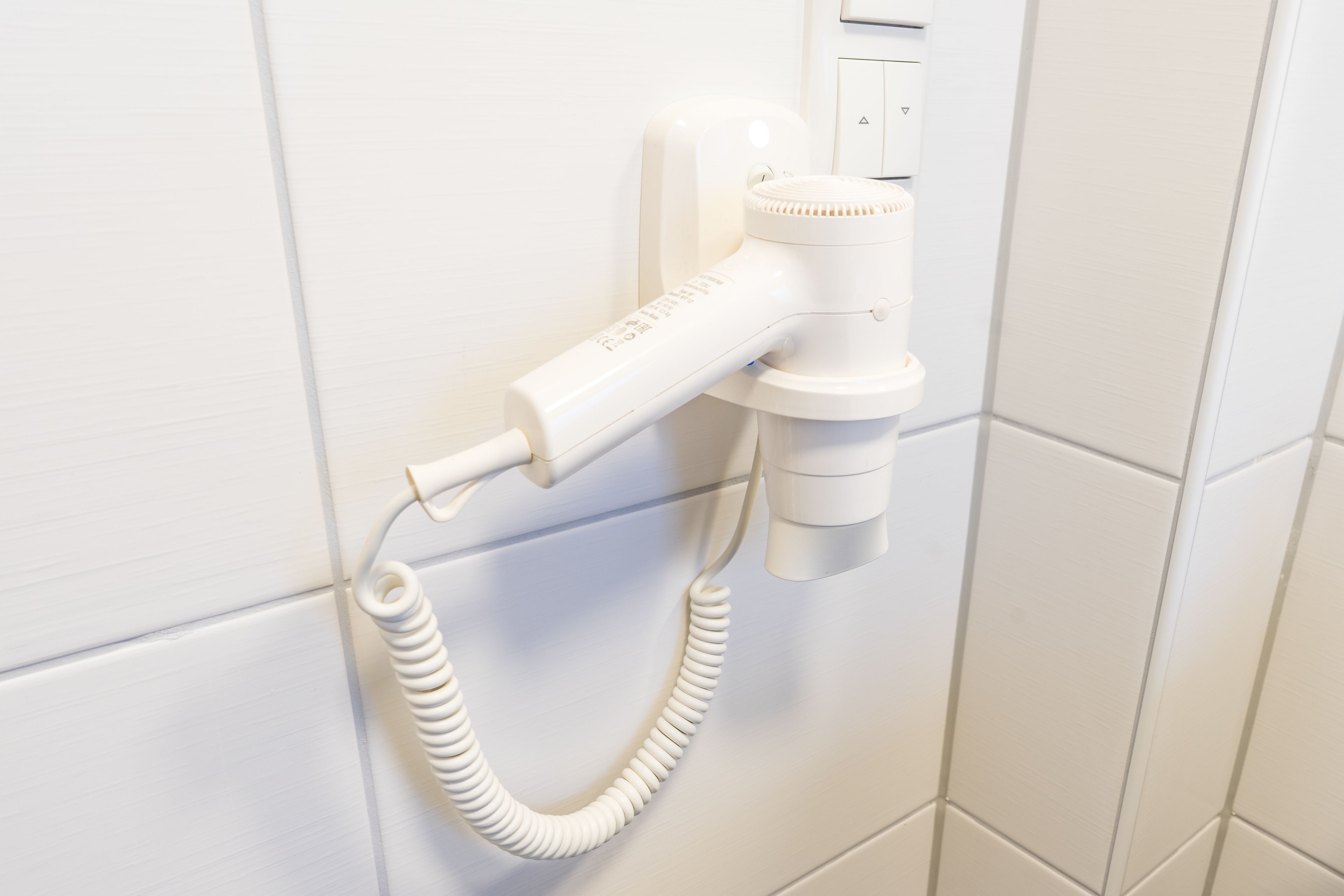 Un secador blanco montado en la pared con un cable enrollado.