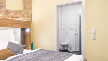 A hotel room with a bed, a wooden headboard, a bathroom with a toilet and a shower.