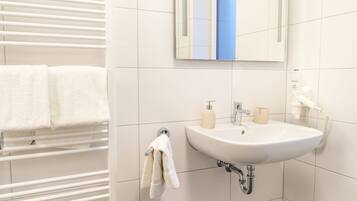 A bathroom with a white sink, a mirror, and a towel rack with two towels.