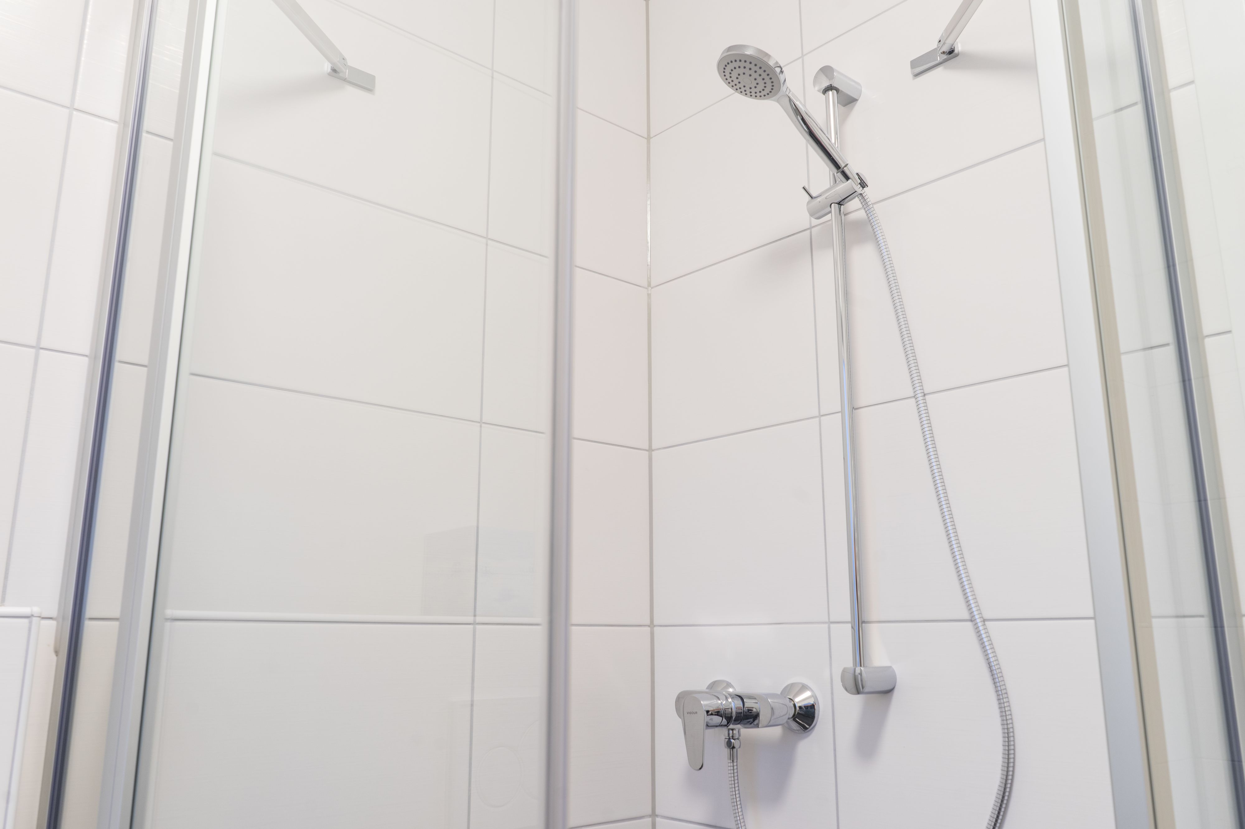 A modern shower with a handheld showerhead and a wall-mounted faucet.