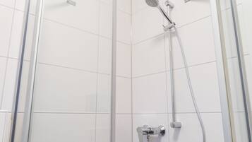 A modern shower with a handheld showerhead and a wall-mounted faucet.