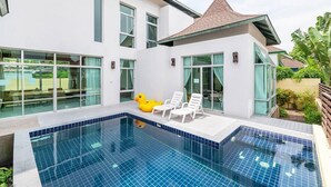 A modern house with a swimming pool, large windows, and a patio area with lounge chairs. - AnB Pool Villa 3BR Glass House in Pattaya (Sattahip)