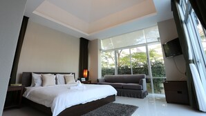 A modern bedroom with a large bed, a sofa, and a TV. - AnB Pool Villa 3BR Glass House in Pattaya (Sattahip)