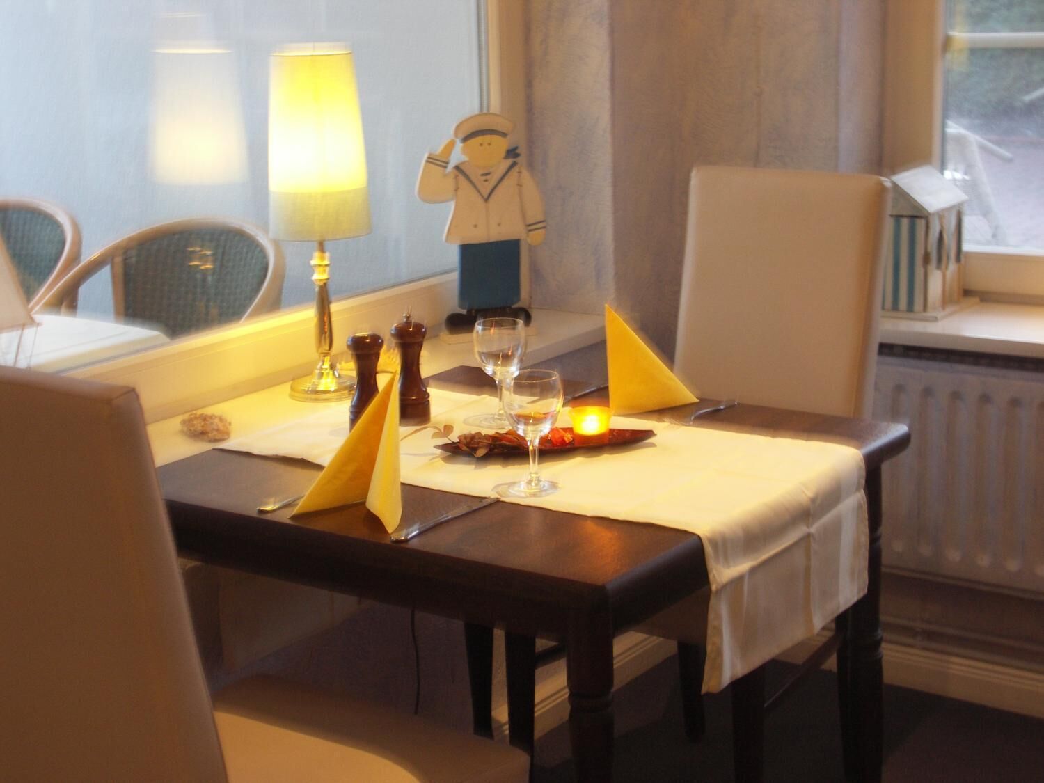 A dining table set with a candle, salt and pepper shakers, a wine glass, and a napkin.