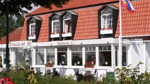 Un bâtiment traditionnel avec un toit recouvert de tuiles rouges, une enseigne de restaurant et un drapeau.