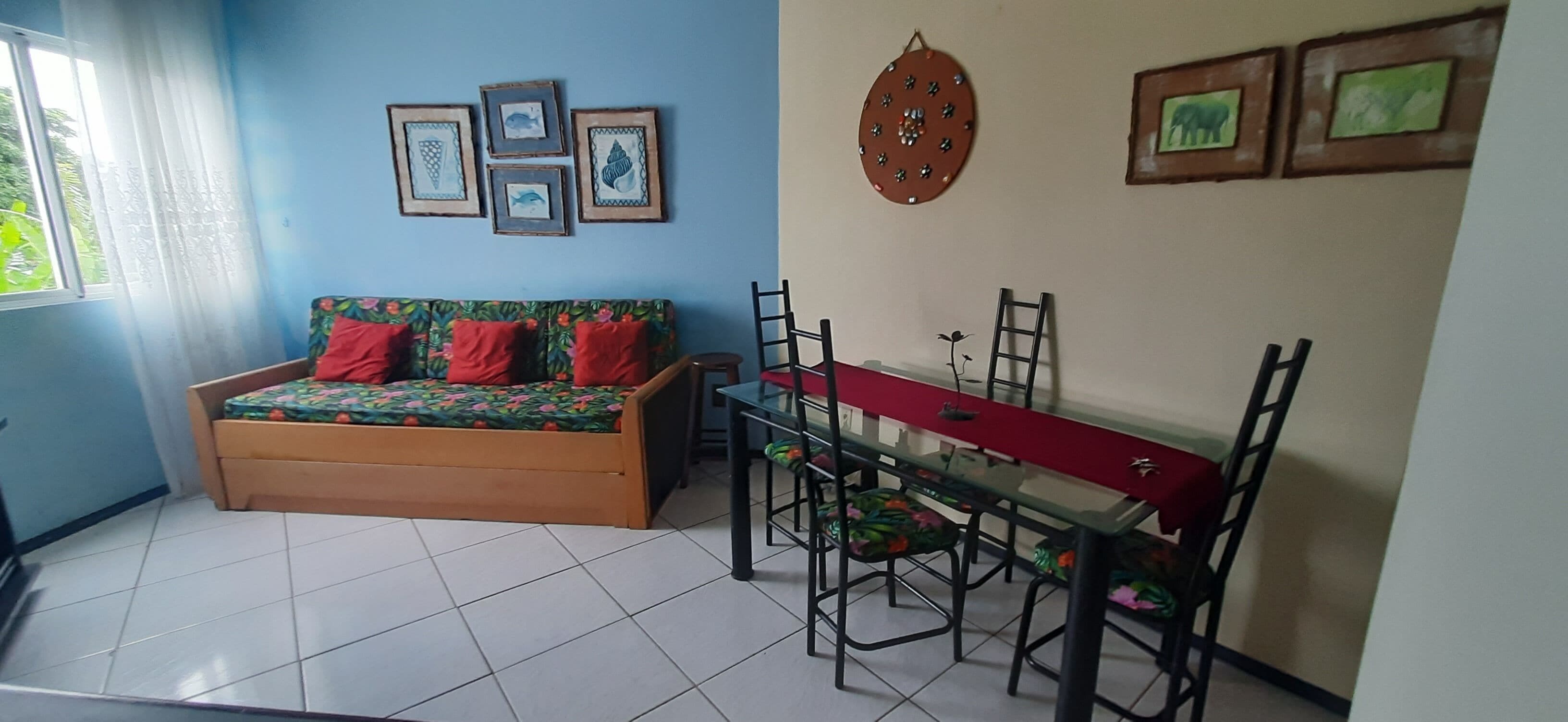 Quarto com sofá, mesa de jantar e cadeiras, além de detalhes decorativos nas paredes.