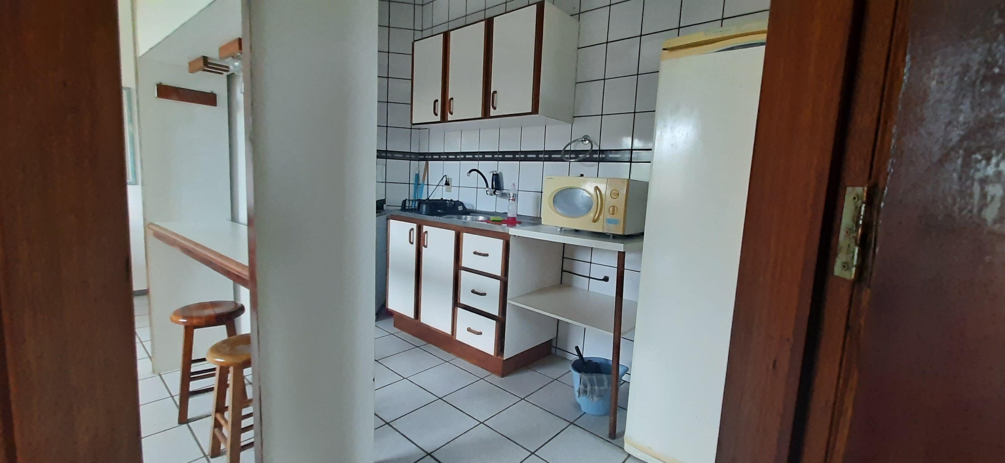A compact kitchen with white cabinets, a microwave, and a sink.