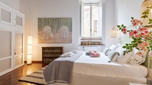 A bedroom with a large bed, a window, a bookshelf, and a painting on the wall. - Rome as you feel - Vetrina Apartment (Rome)