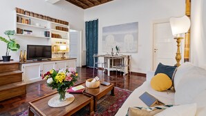 A living room with a TV, bookshelves, a dining table, and a sofa. - Rome as you feel - Vetrina Apartment (Rome)