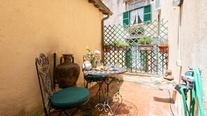 A small outdoor patio with a table and chairs, a large vase, and a potted plant. - Rome as you feel - Vetrina Apartment (Rome)