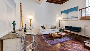 A living room with a wooden ceiling, a white sofa, a coffee table, and a blue armchair. - Rome as you feel - Vetrina Apartment (Rome)