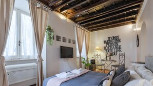 Een slaapkamer met een bed, een televisie, een bureau en een inspirerende quote op de muur.