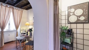 Een eetgedeelte met een tafel gedekt voor twee personen, een lamp en een wandbord met keukengerei.