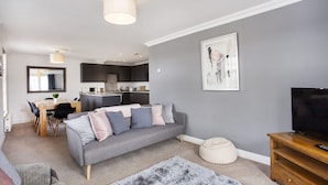 Una sala de estar moderna con un sofá gris, una mesa de centro y un mueble para televisor.