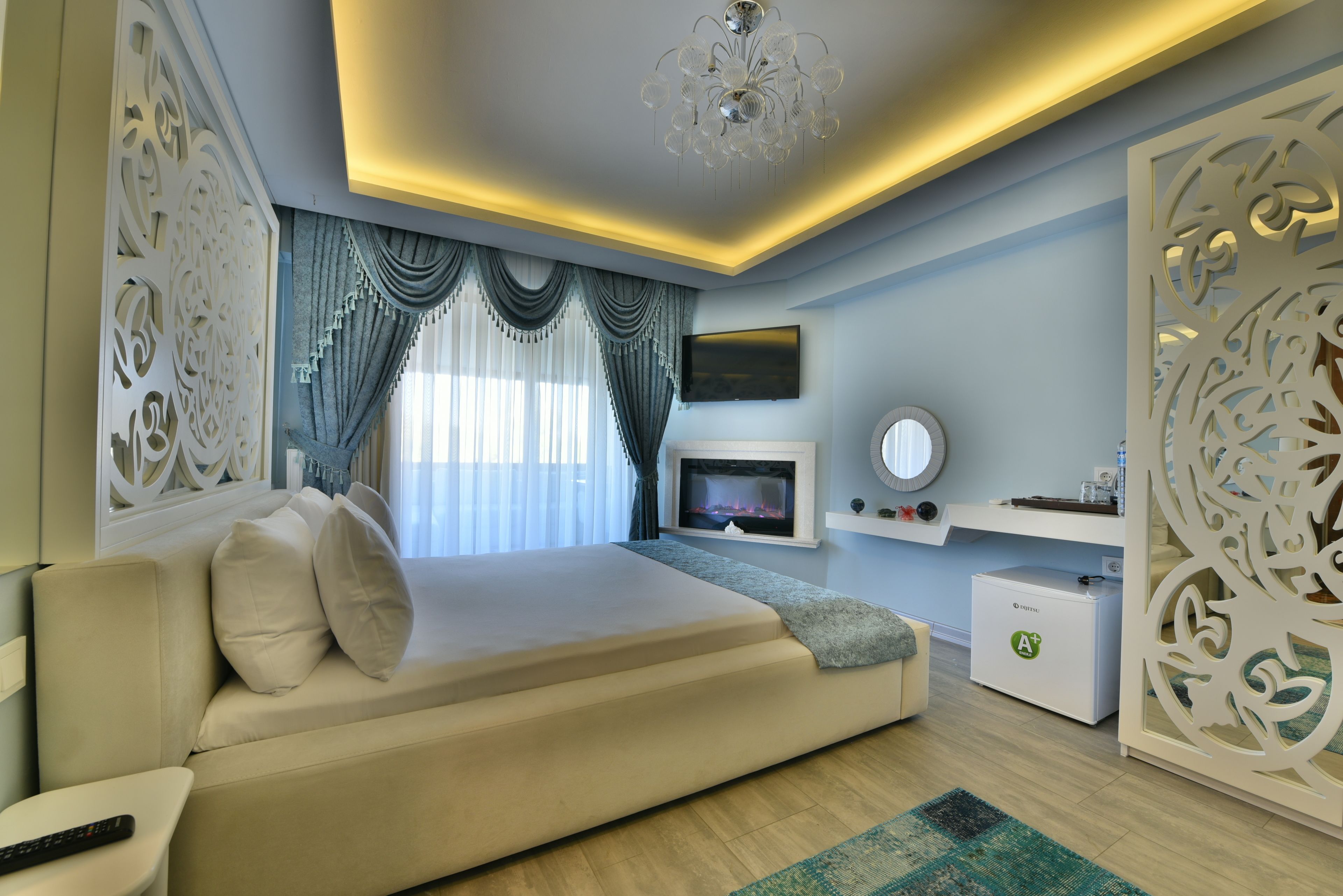 Un dormitorio moderno con sofá cama, televisor de pantalla plana, chimenea, paneles decorativos en la pared y un candelabro.