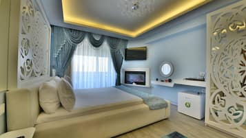 Un dormitorio moderno con sofá cama, televisor de pantalla plana, chimenea, paneles decorativos en la pared y un candelabro.