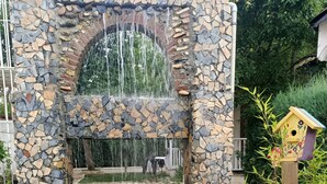 A stone water feature with a waterfall and a pond with lily pads. - Kartepe Kosku (Kartepe)