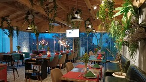 A restaurant with wooden ceilings, hanging plants, and tables set for dining. - Kartepe Kosku (Kartepe)