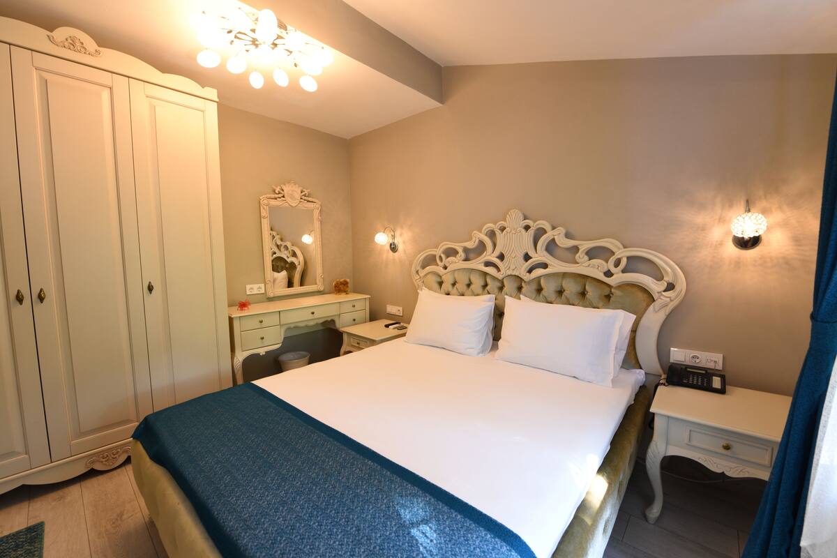 Un dormitorio con una cama grande, un armario, una cómoda con espejo y lámparas de noche.