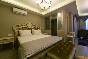 Habitación de hotel con una cama grande, un tocador con espejo, una silla y una ventana con cortinas.