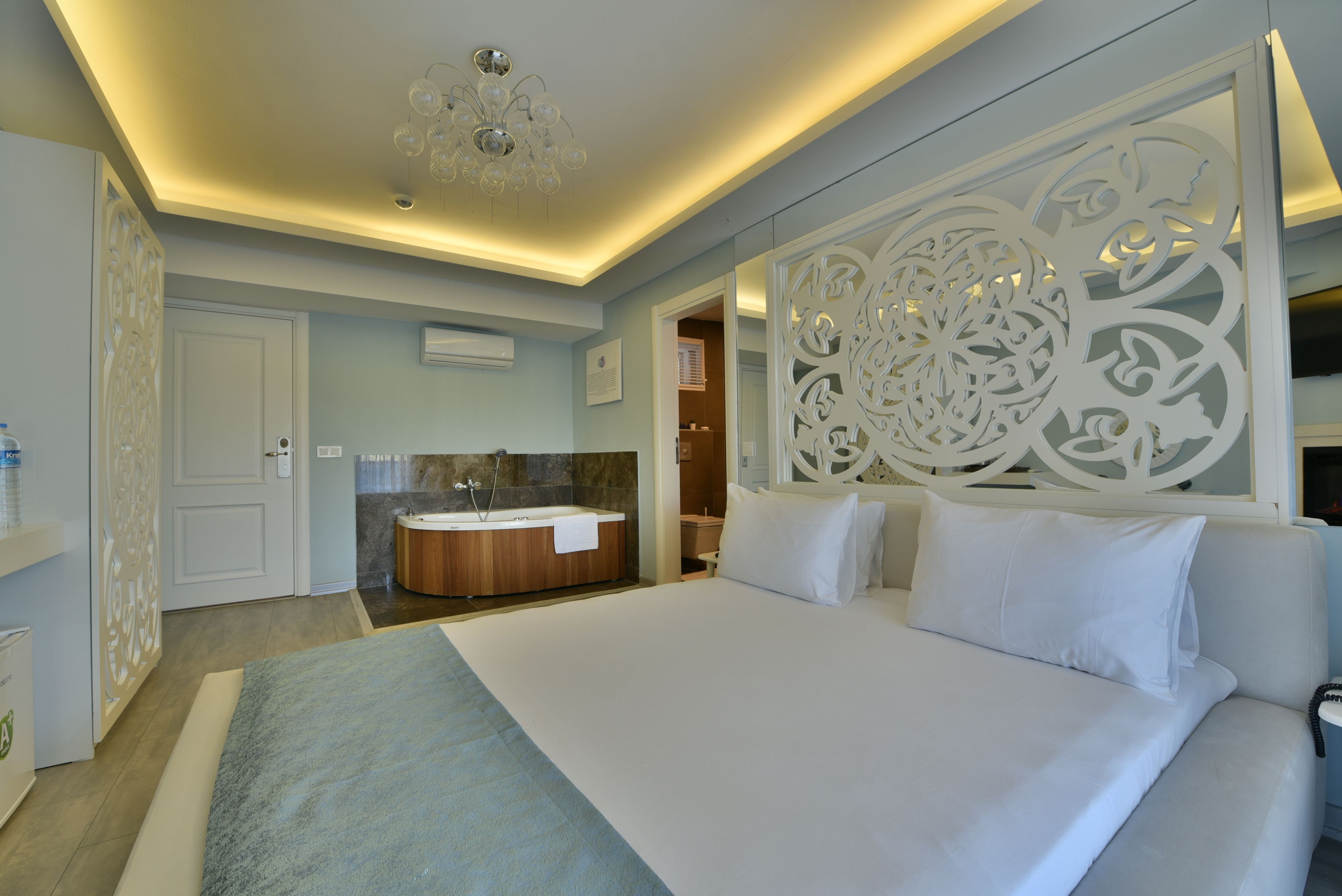 Una habitación de hotel moderna con una cama grande, un baño independiente con bañera y un panel decorativo en la pared.
