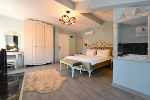 Un dormitorio con una cama grande, un tocador con espejo, un armario y una araña.